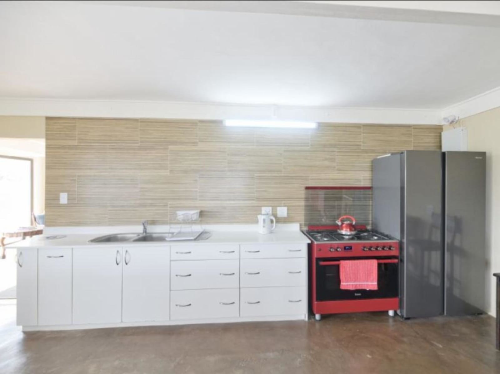 Gans-te-Ver's kitchen — white cabinetry, a red gas stove and oven, double-door fridge-freezer and everything needed for self-catering.