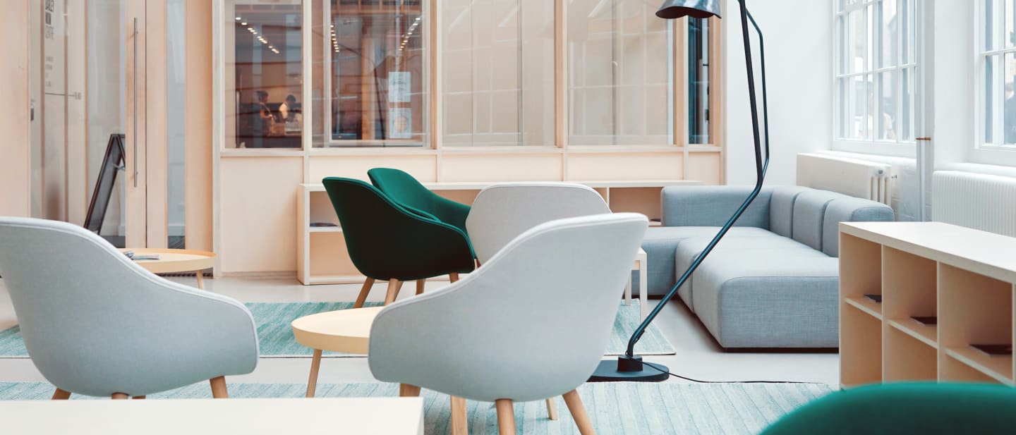 A quiet room with pale armchairs arranged around a low table by tall windows