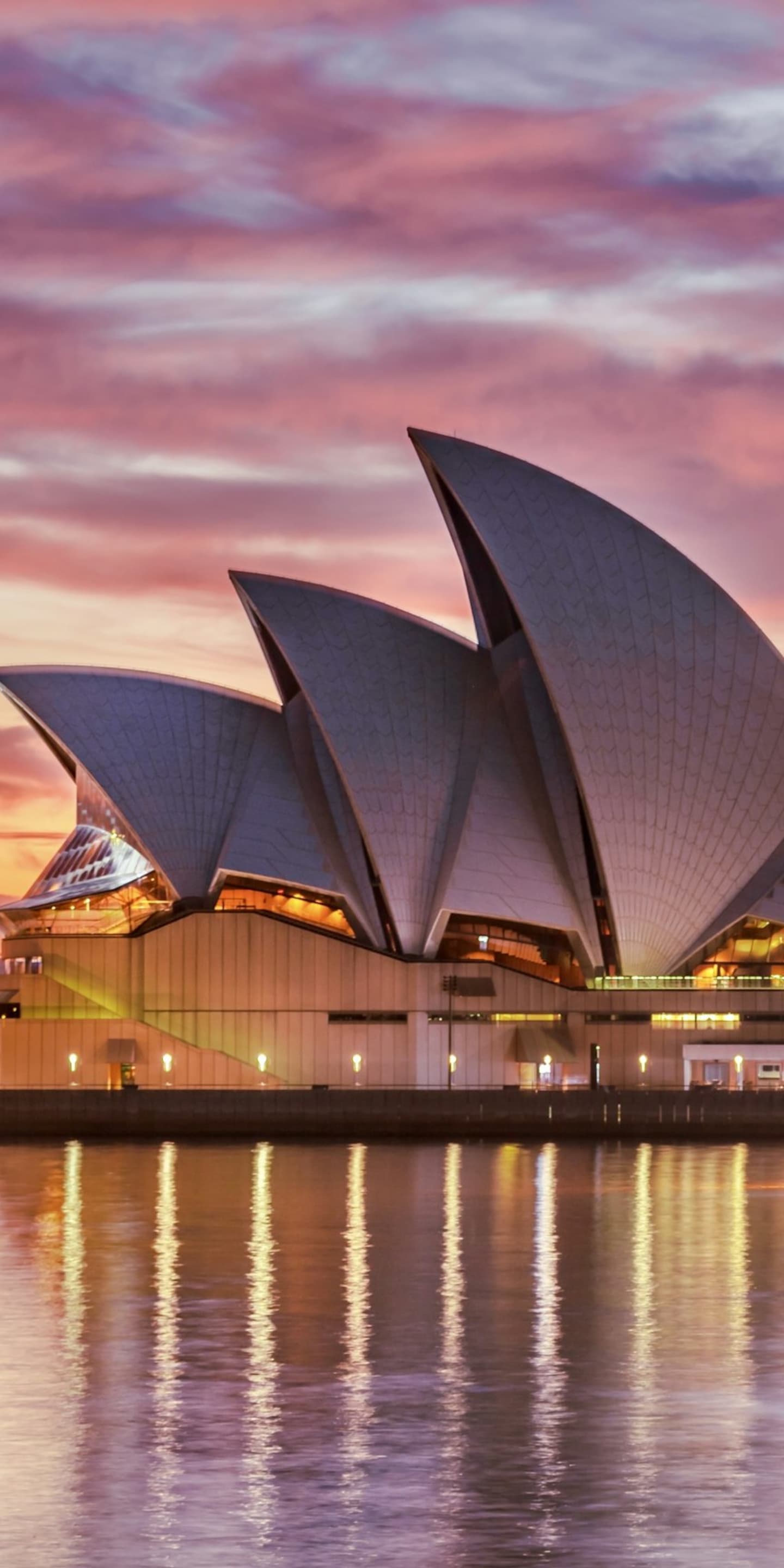 Sydney Opera House lit against a pink and violet sunset over the harbour