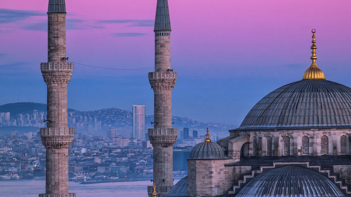 The domes and minarets of the Blue Mosque in Istanbul against a pink dusk sky