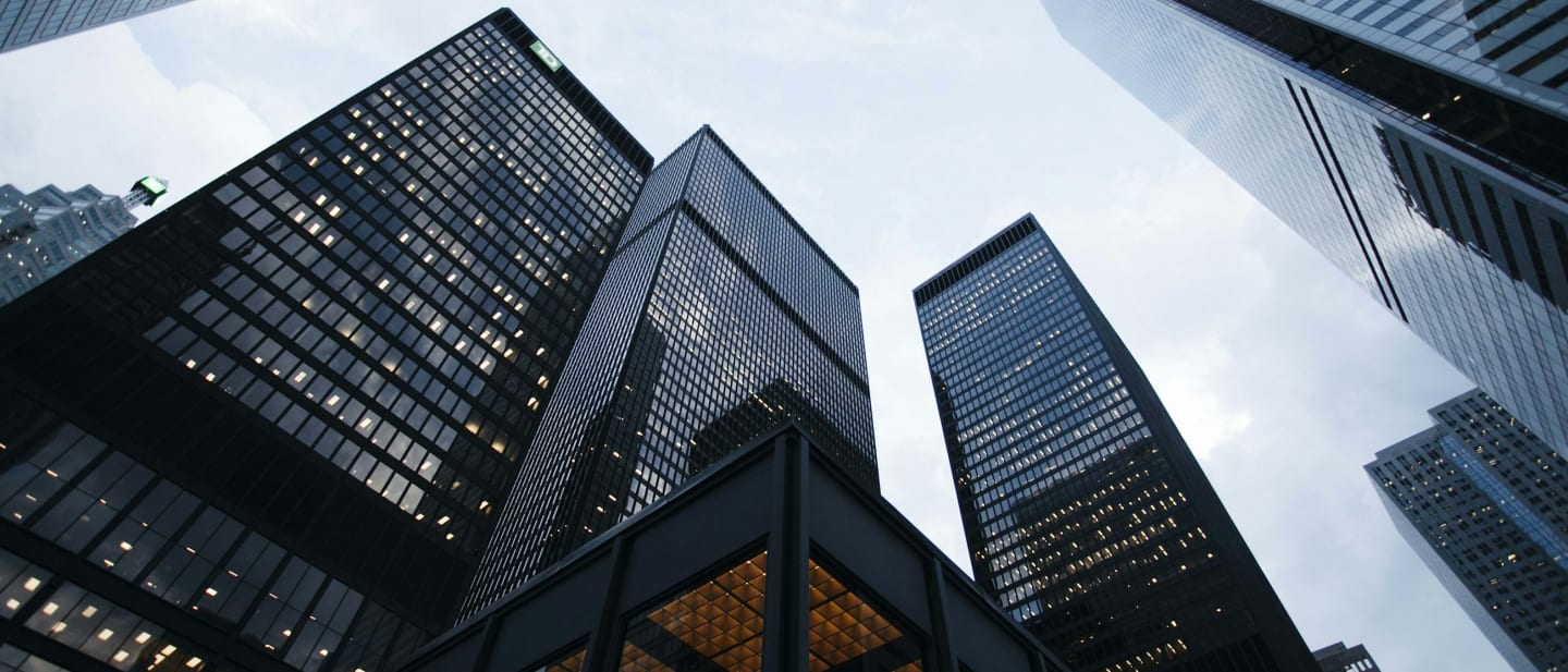 Glass office towers photographed looking upward against a bright sky