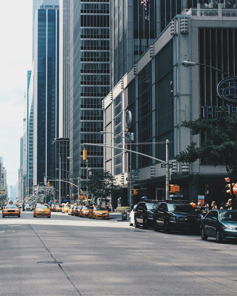Traffic moving along a city avenue between tall office towers