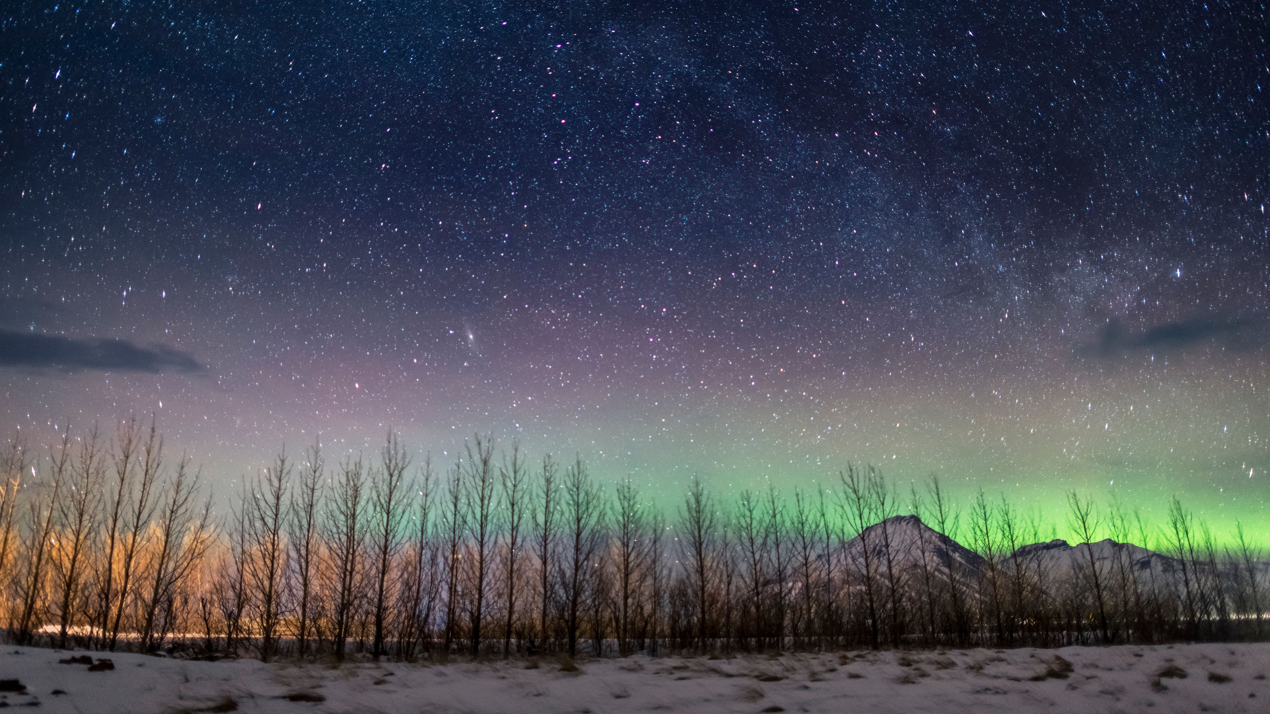 Green northern lights over a lighthouse at night