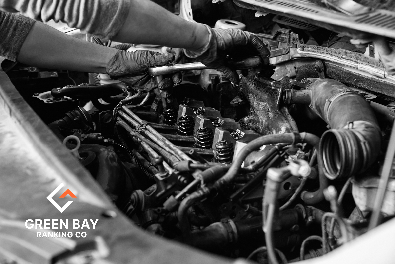 Auto mechanic repairing engine components under the hood at an auto repair shop in Green Bay, Wisconsin.