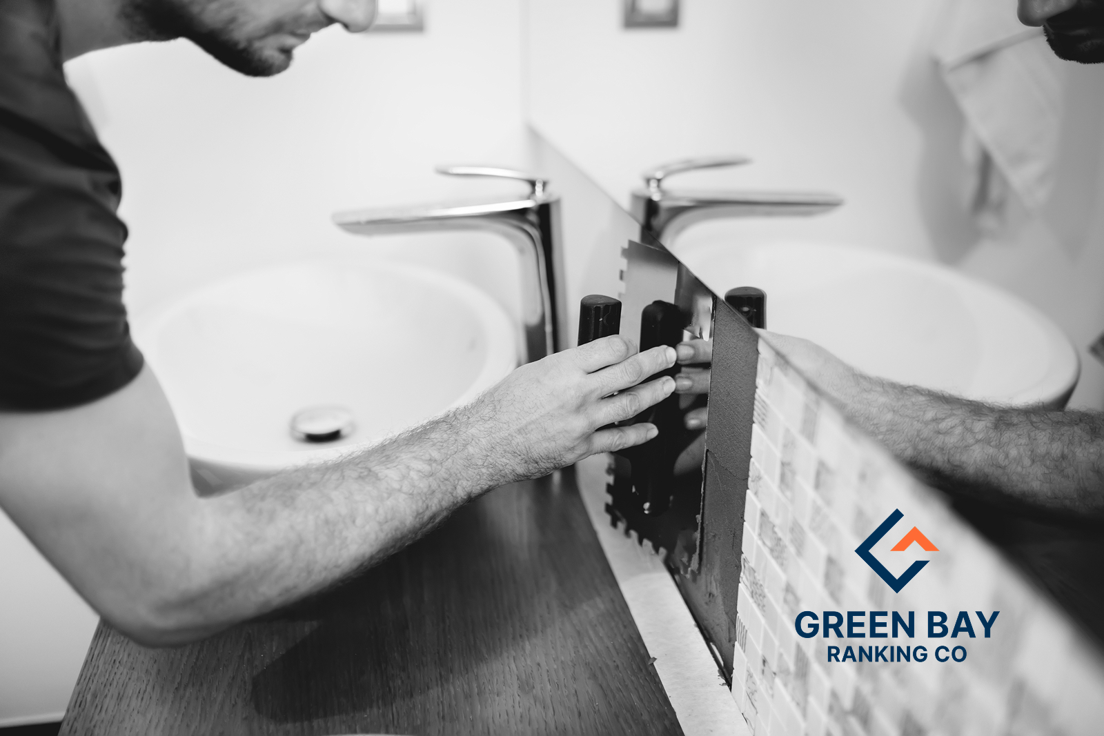 Contractor installing a bathroom backsplash beside a sink, with Green Bay Ranking Co. branding.