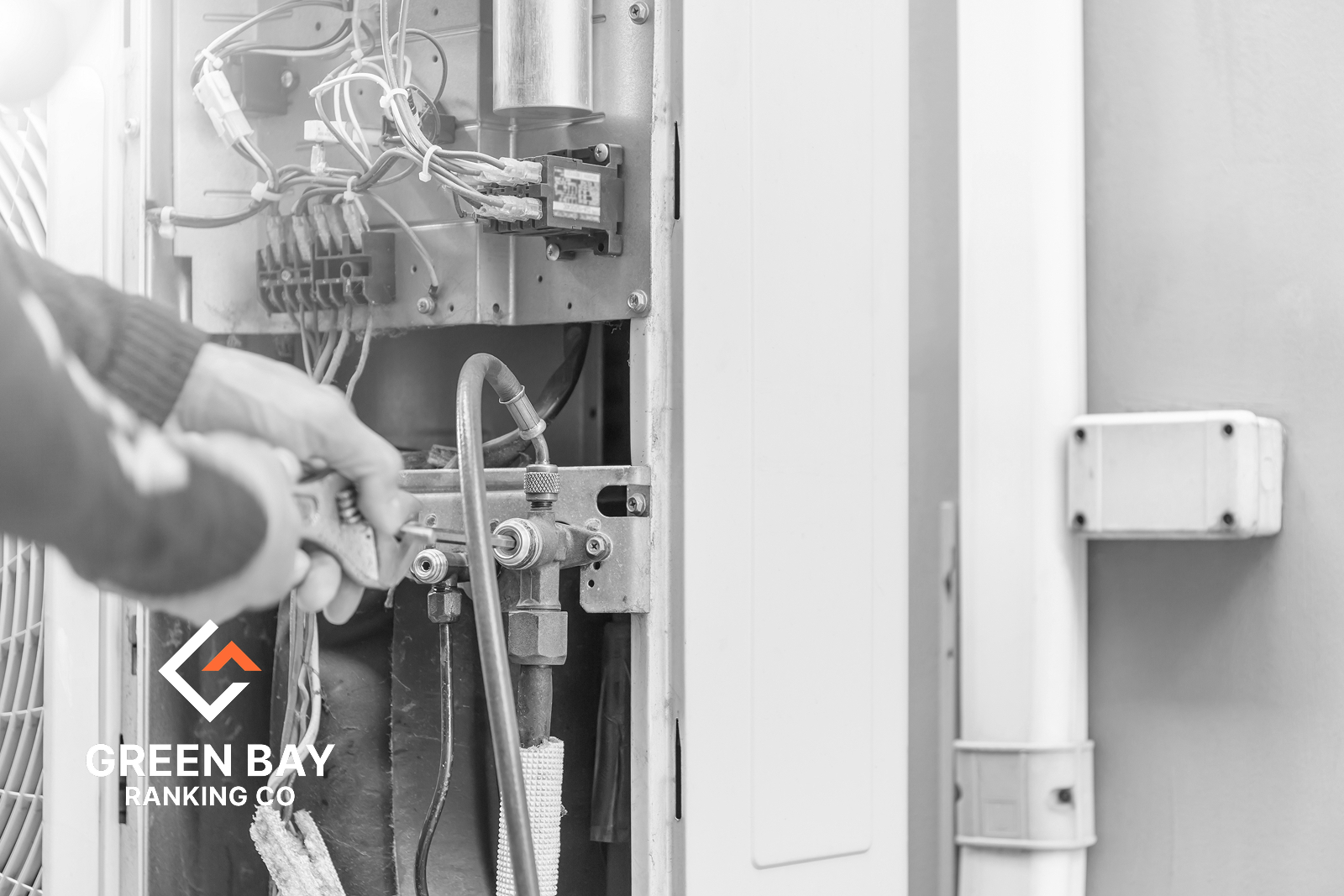 HVAC technician servicing internal components of an outdoor heating and cooling unit in Green Bay, Wisconsin.