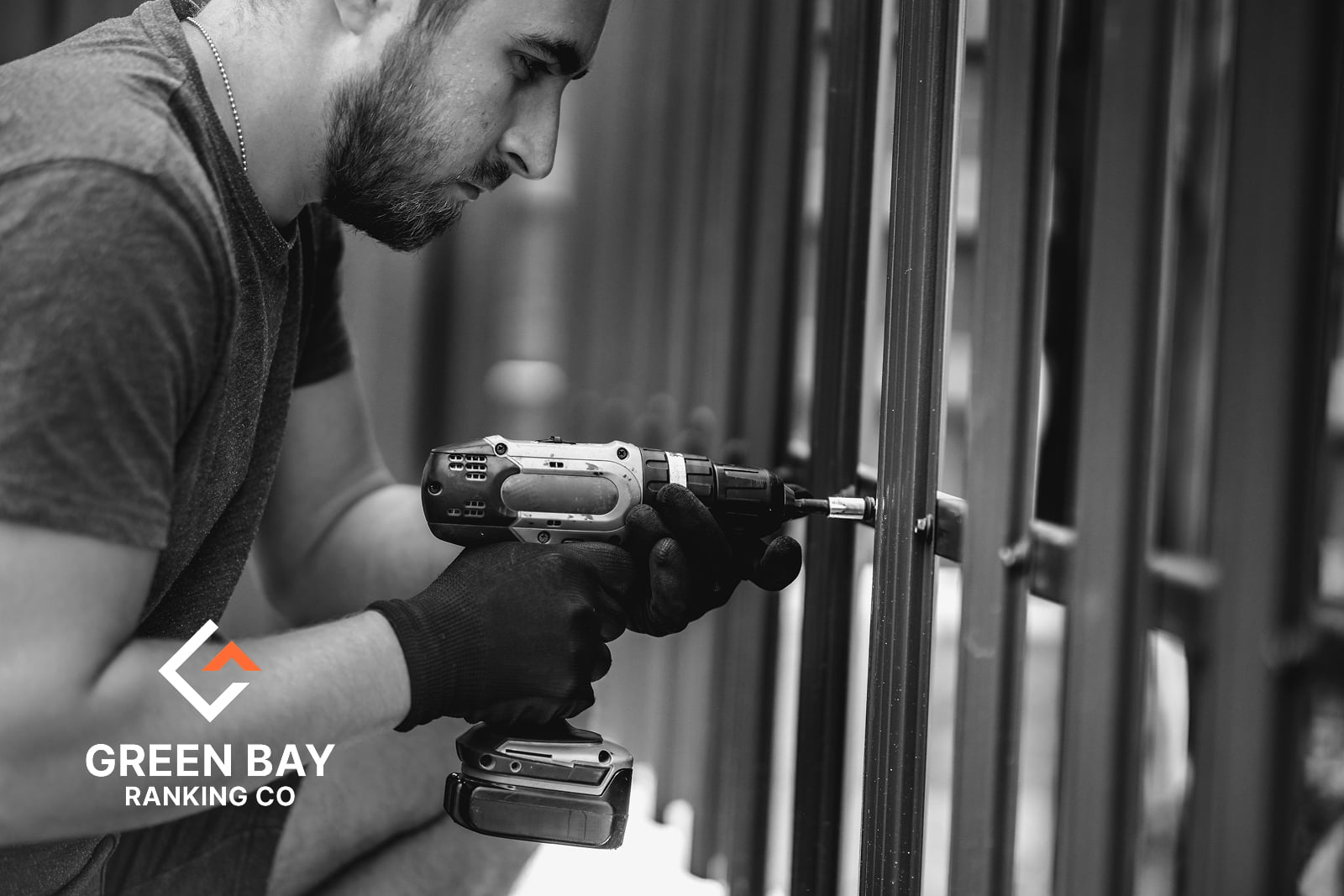 Fence contractor using a cordless drill to install metal fence panels in Green Bay, WI.