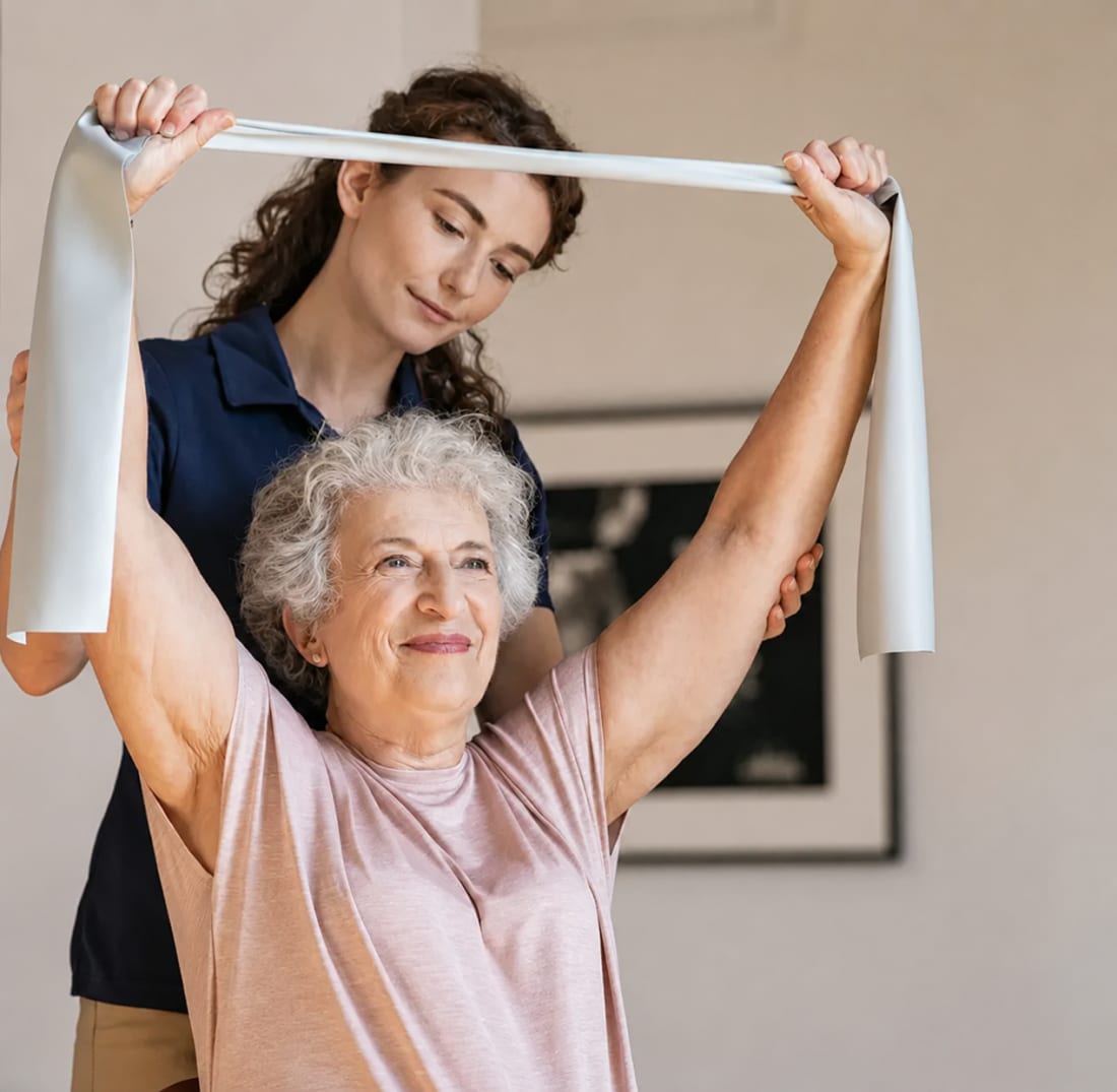 Une coach VitaliHome guide une personne avec un élastique de résistance dans son salon