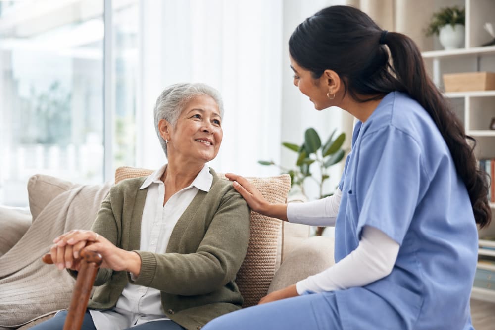 Un adulte d'une soixantaine d'années en conversation avec un proche ou un professionnel de santé dans un salon lumineux et chaleureux
