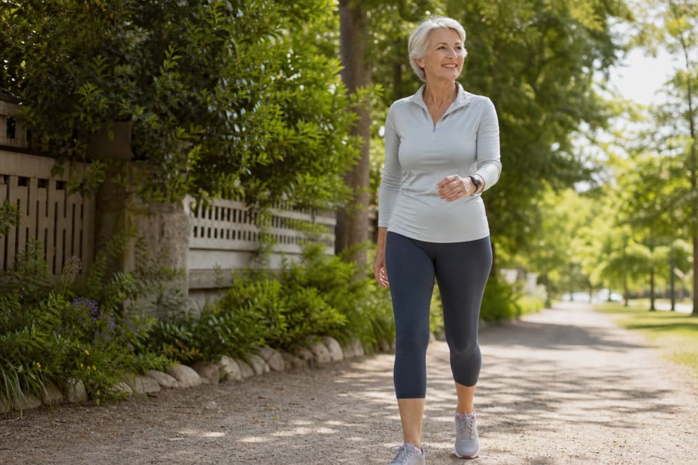 Femme active de 65 ans en marche rapide sur un chemin de parc, en tenue de sport légère