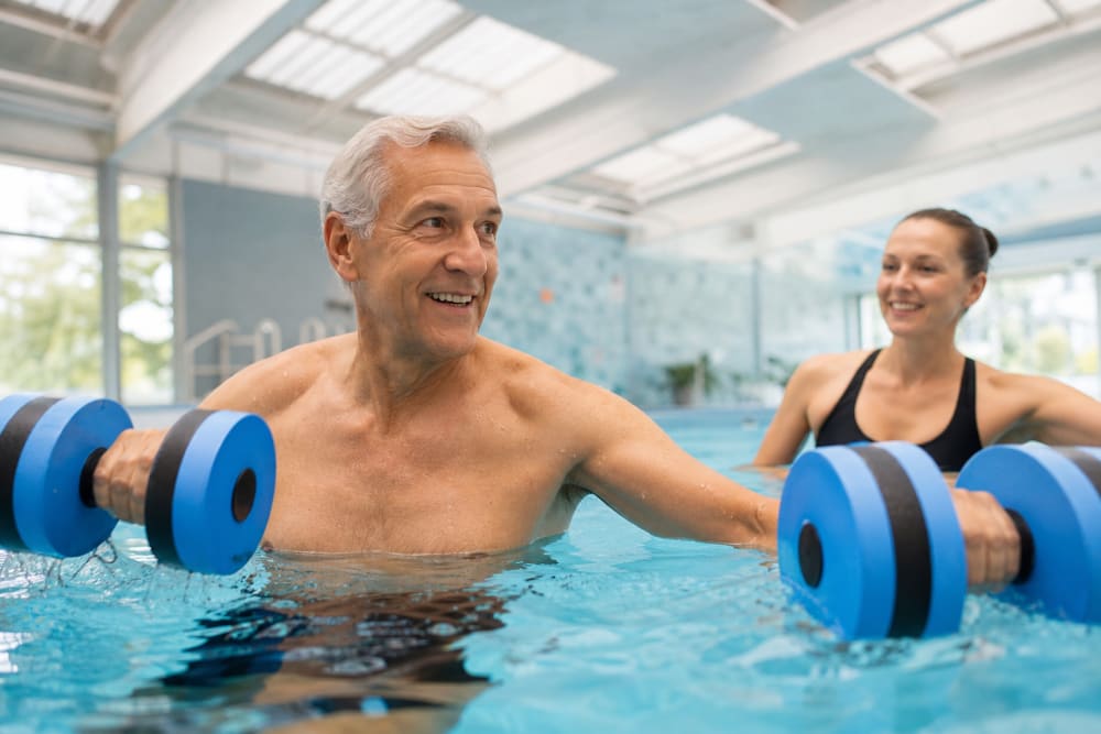 Homme pratiquant l'aquagym dans une piscine lumineuse, activité recommandée pour soulager les douleurs dorsales