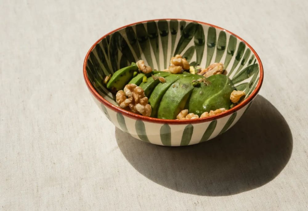 Une assiette composée d'un avocat découpé et de noix