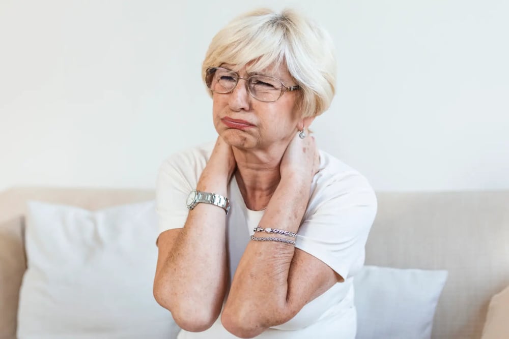 une dame se tient la nuque de douleurs