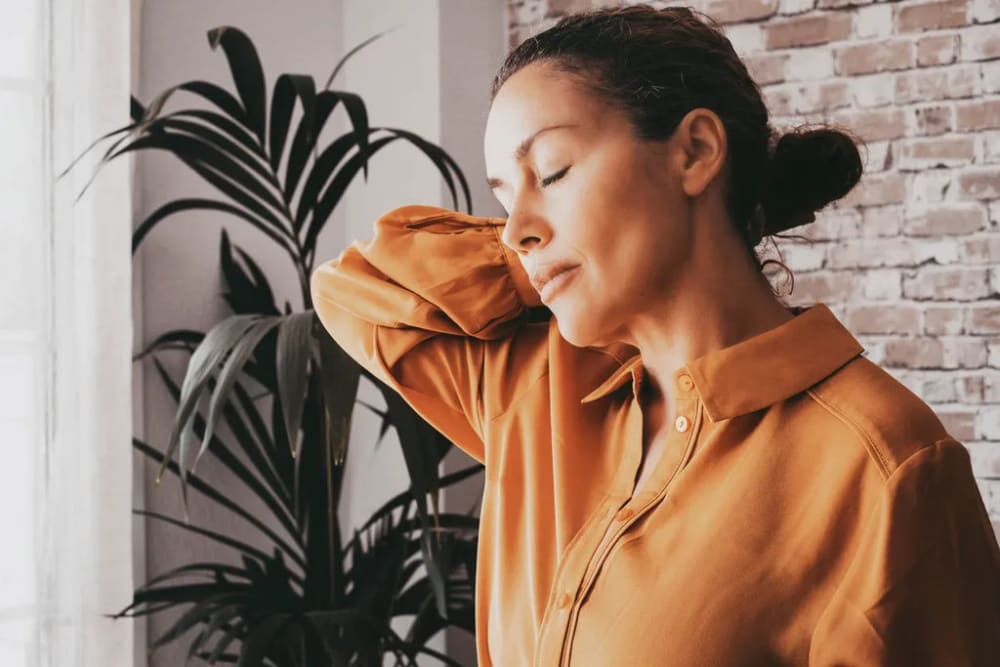 Une dame se tient la nuque avec la main droite car elle souffre
