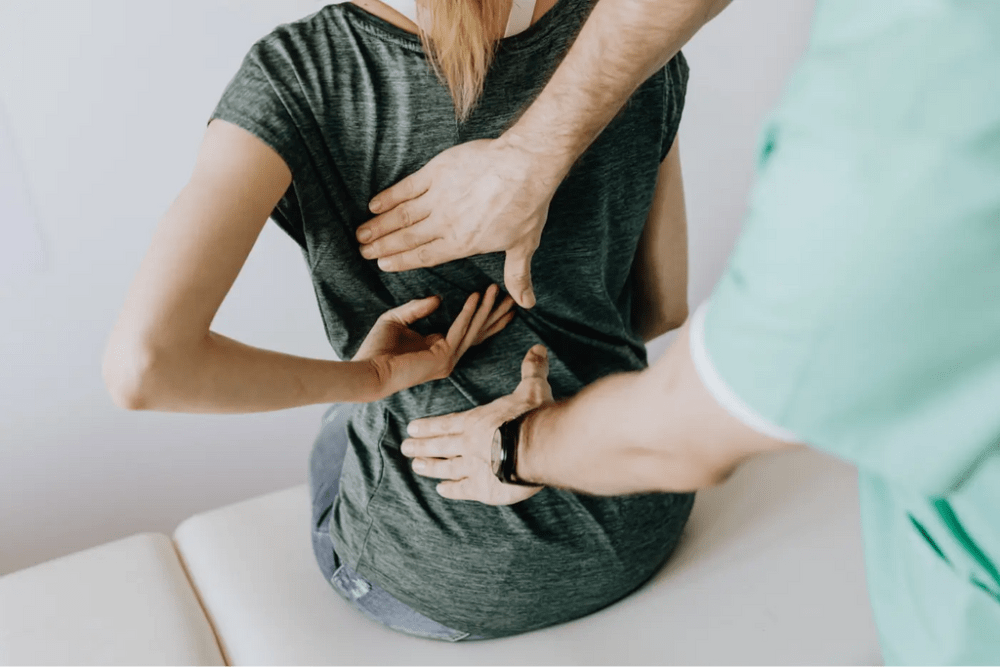 médecin qui appuie sur le bas du dos d'une femme assise sur une table