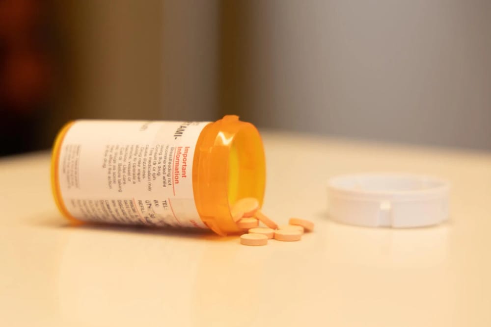 Une boite de médicaments est tombée sur une table et les gélules sont éparpillées.