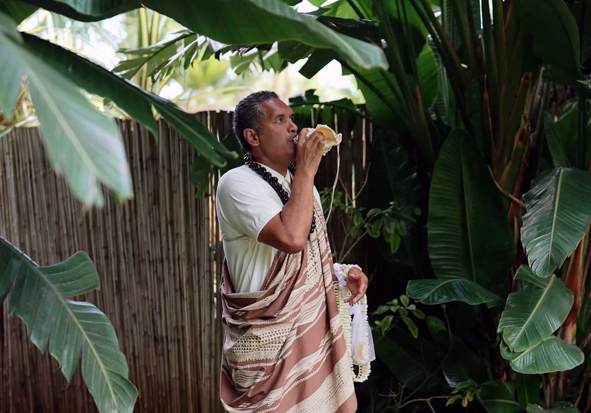 Officiant Ryan Souza blowing the conch shell (the pū) to begin the wedding ceremony.