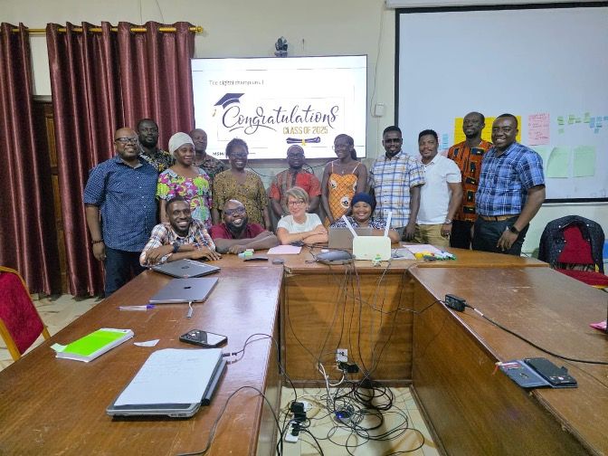Diverse group smiling around a conference table with 'Congratulations' on a projector screen.