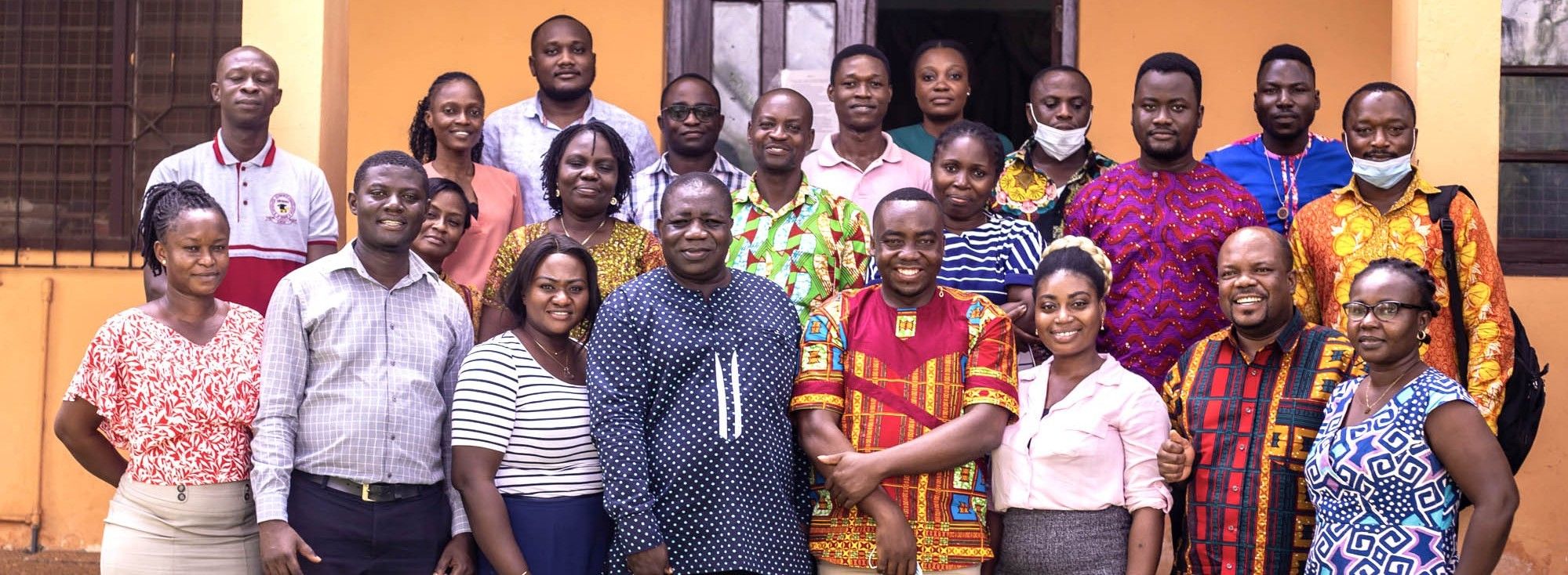 A large diverse group of smiling adults posing together for a photo indoors.