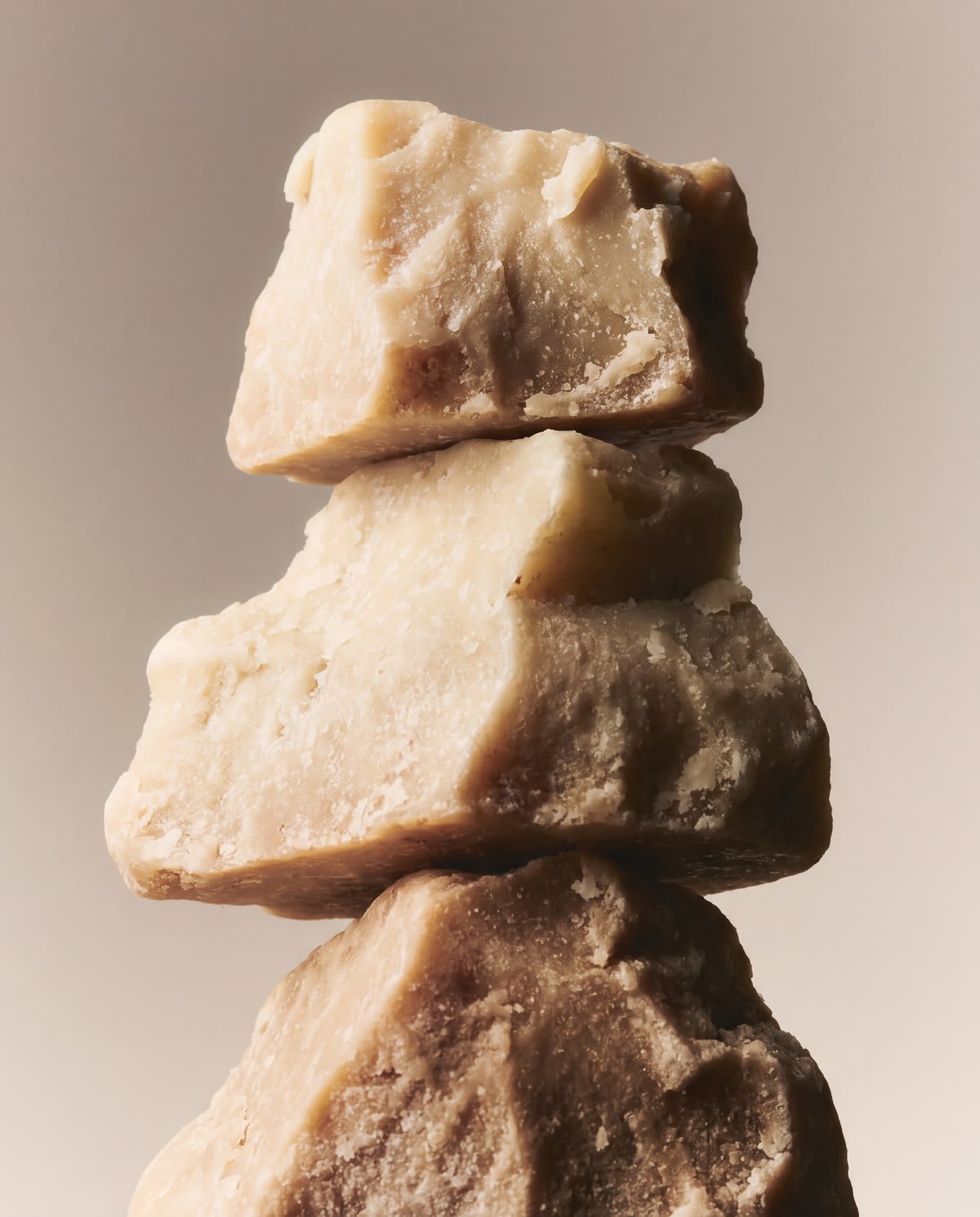 Three raw blocks of shea butter stacked beside a can of Comfort Mousse