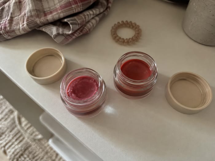 Two open pots of Tinted Balm in Rose Pink and Terracotta on a bathroom shelf