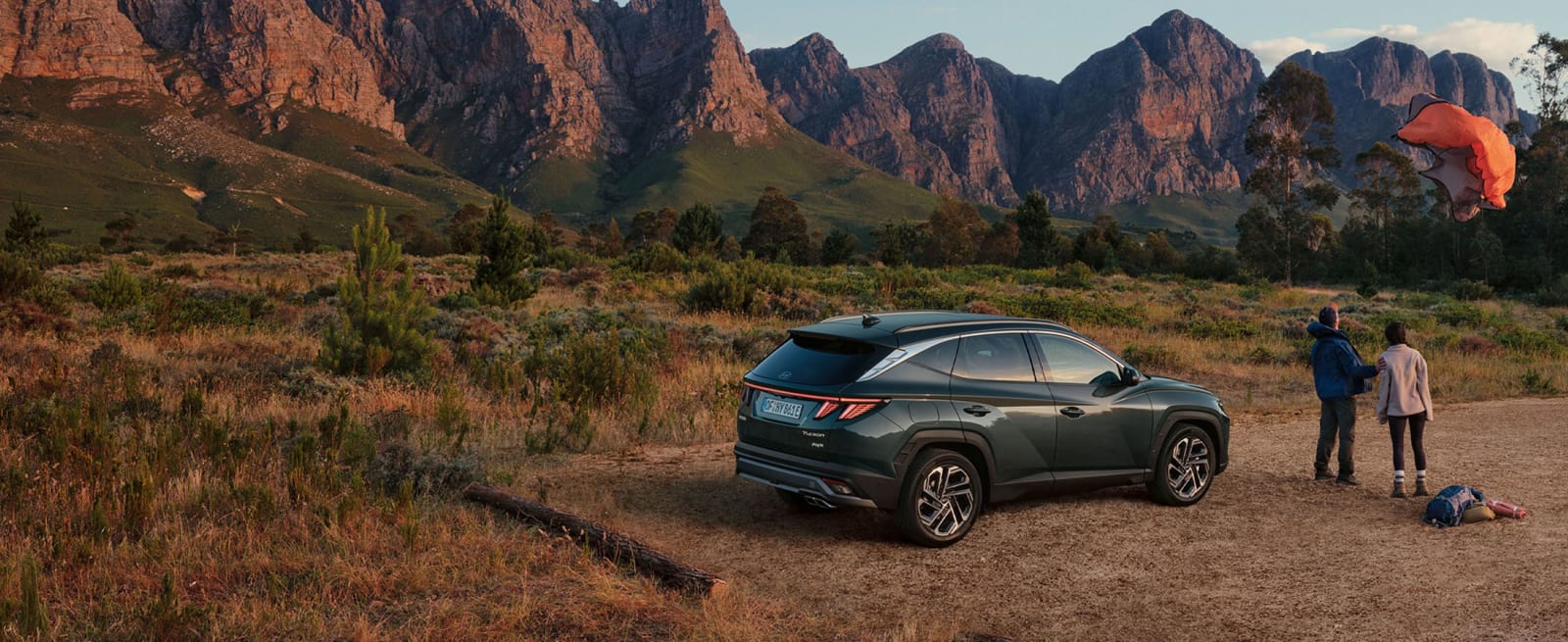 Nainen ja mies katsomassa pois lentävää telttaa vuoristomaisemassa. Vieressä parkissa vihreä Hyundai Tucson