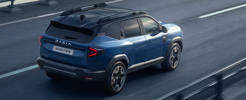 Sininen Dacia Bigster ajossa sillalla, kuvattuna takaapäin