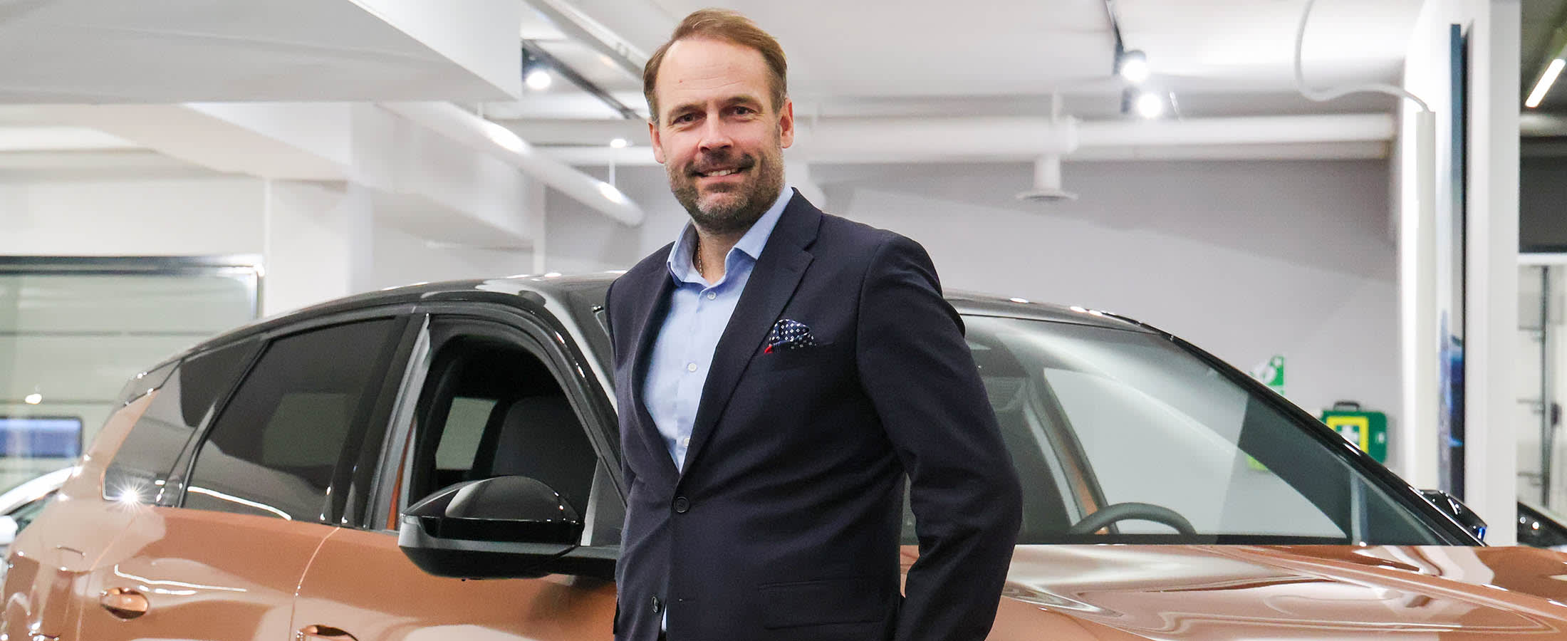 Mies nojaa kuparinväriseen autoon.