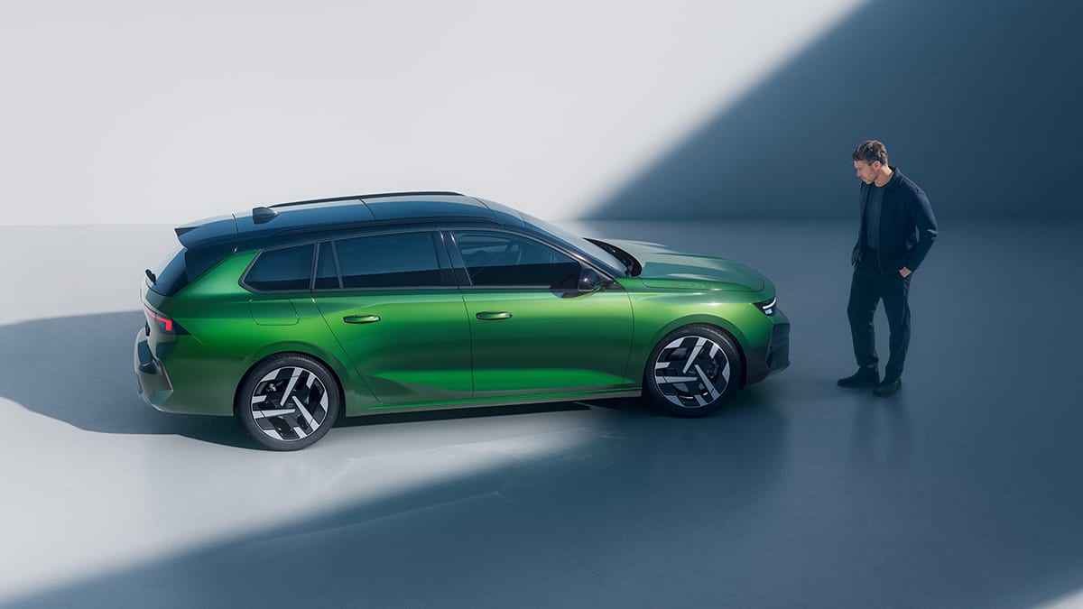 Mies seisoo vihreän Opel Astra Sports Tourerin edessä