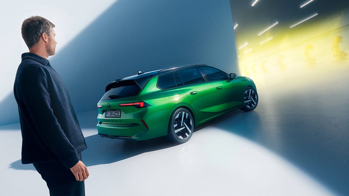 Mies seisomassa vihreän Opel Astra Sports Tourerin takana