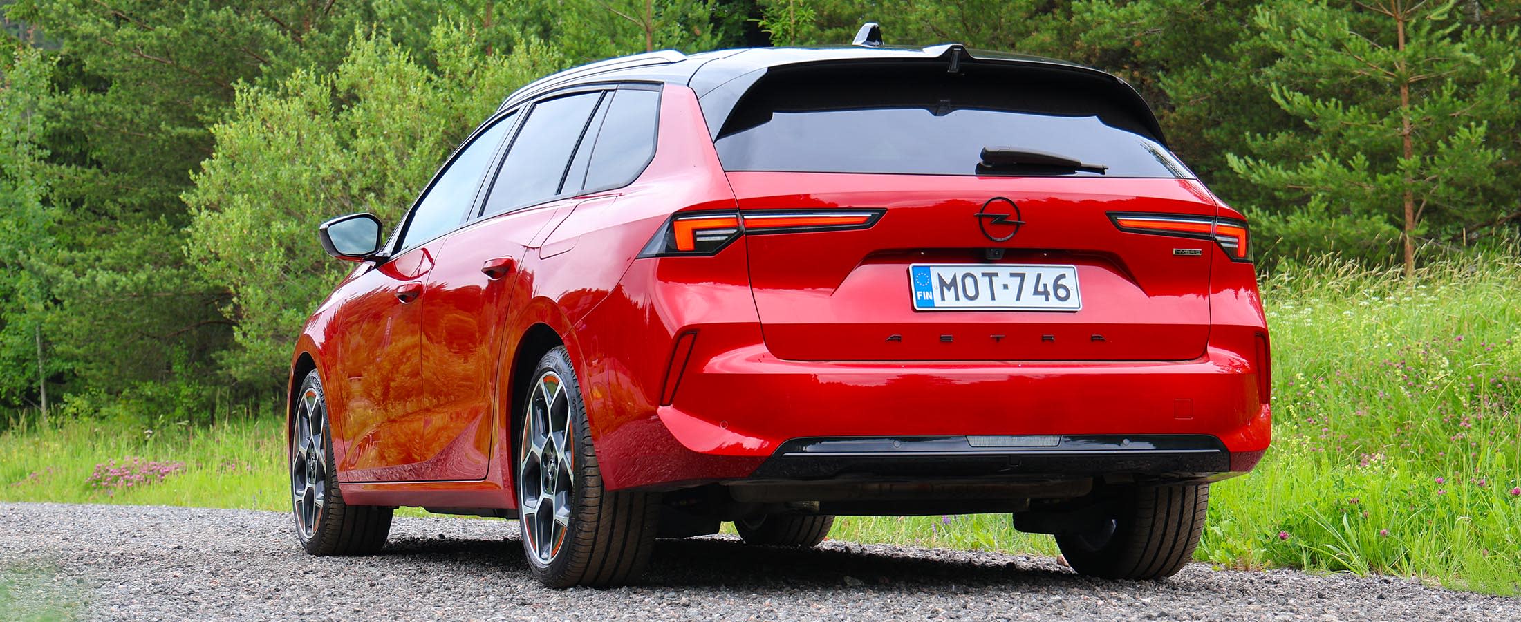 Punainen Opel Astra takaa. Taustalla kesäinen maisema.
