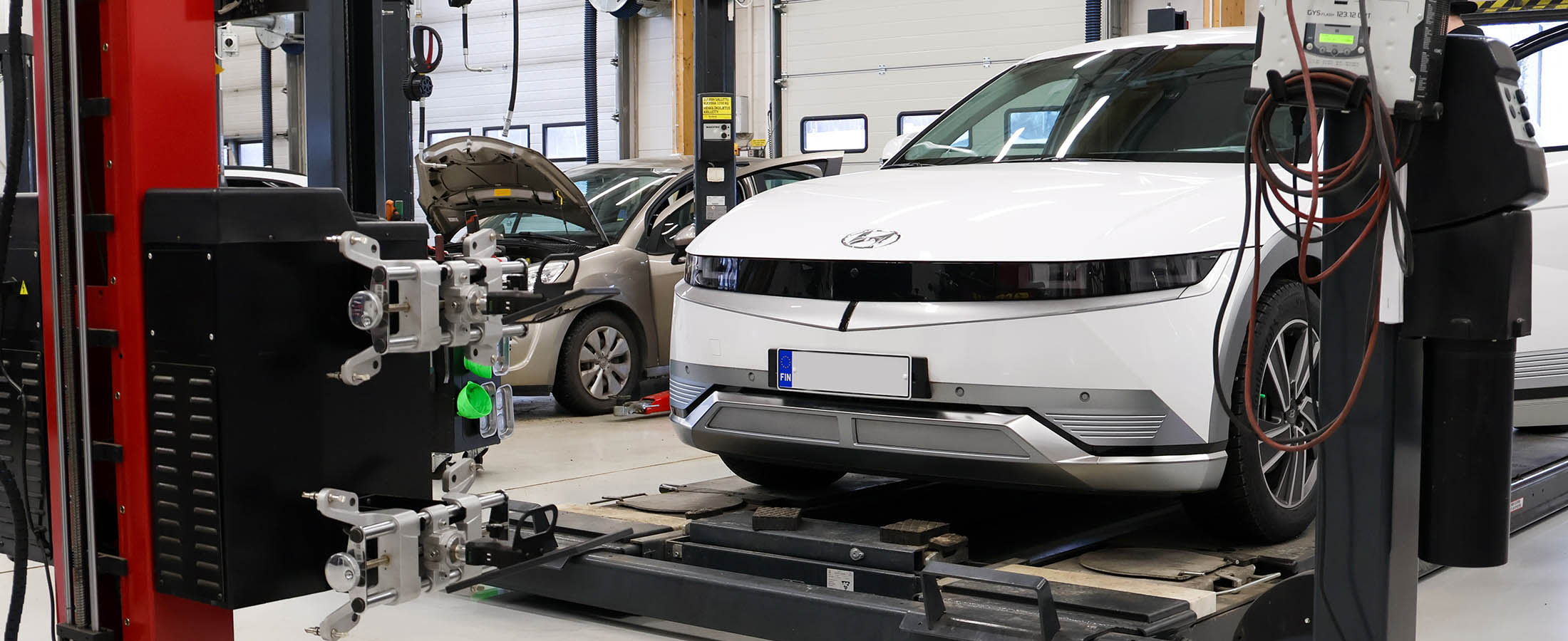 Valkoinen Hyundai IONIQ 5 huoltohallissa nosturin päällä