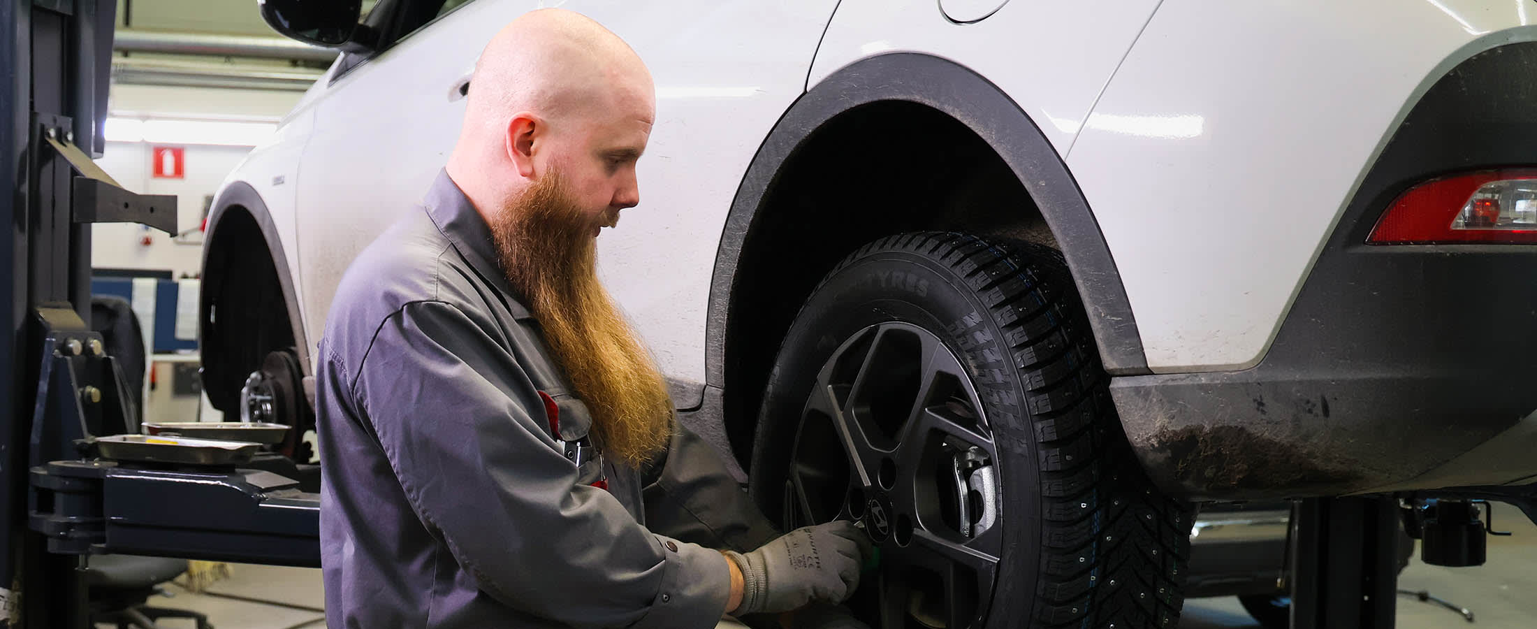 Mies vaihtaa autoon renkaita.