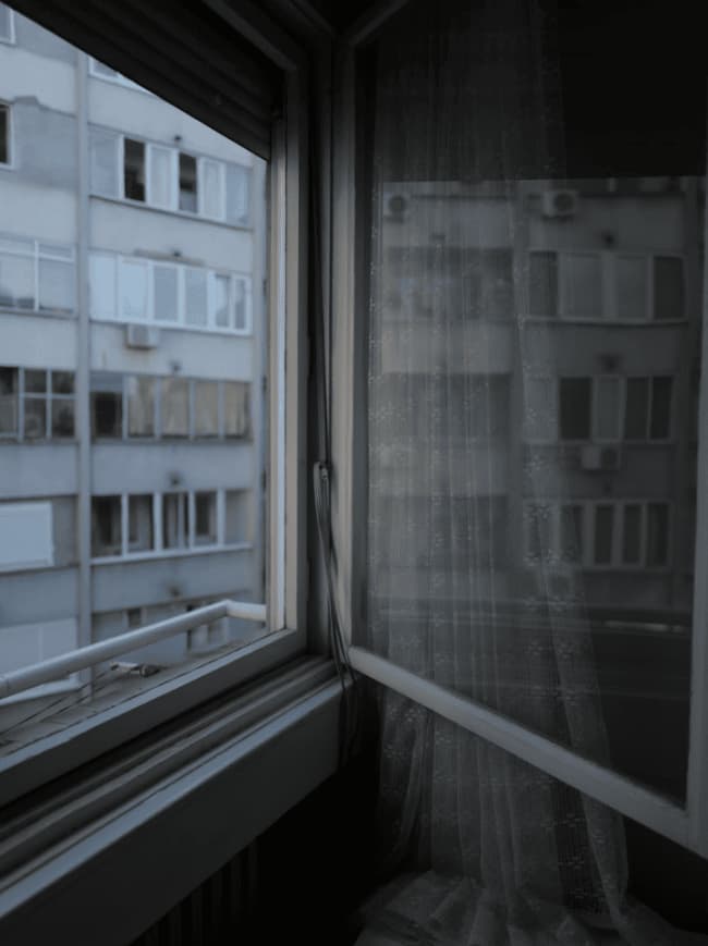A window onto the block opposite, curtain half-drawn.