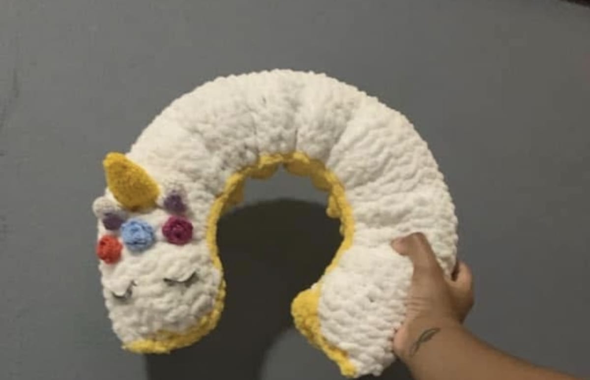 Almohada para viaje realizada a crochet con hilo “chunky” y algodón sintético como relleno. Mide aproximadamente 13”de ancho .