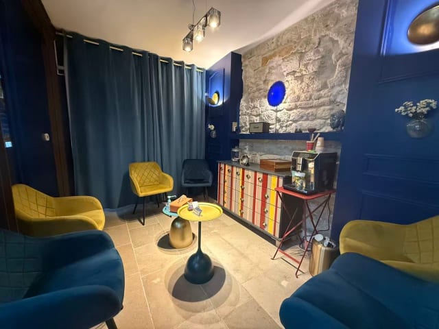 La salle d’attente du cabinet, avec ses fauteuils et son mur de pierre.