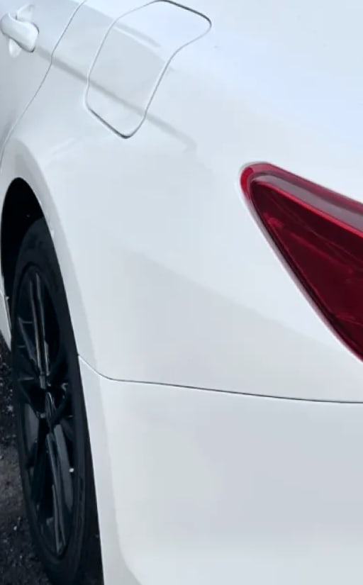 Dent worked out of a white Camry panel, after repair
