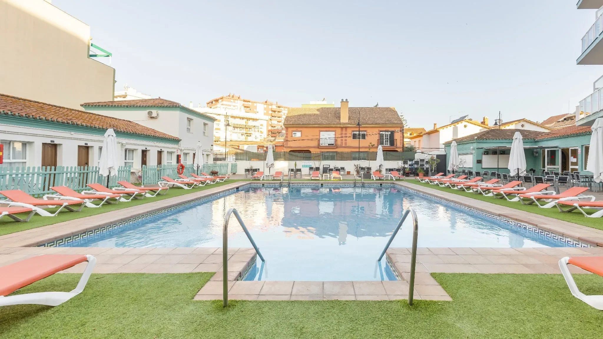 Piscina exterior con tumbonas y sombrillas