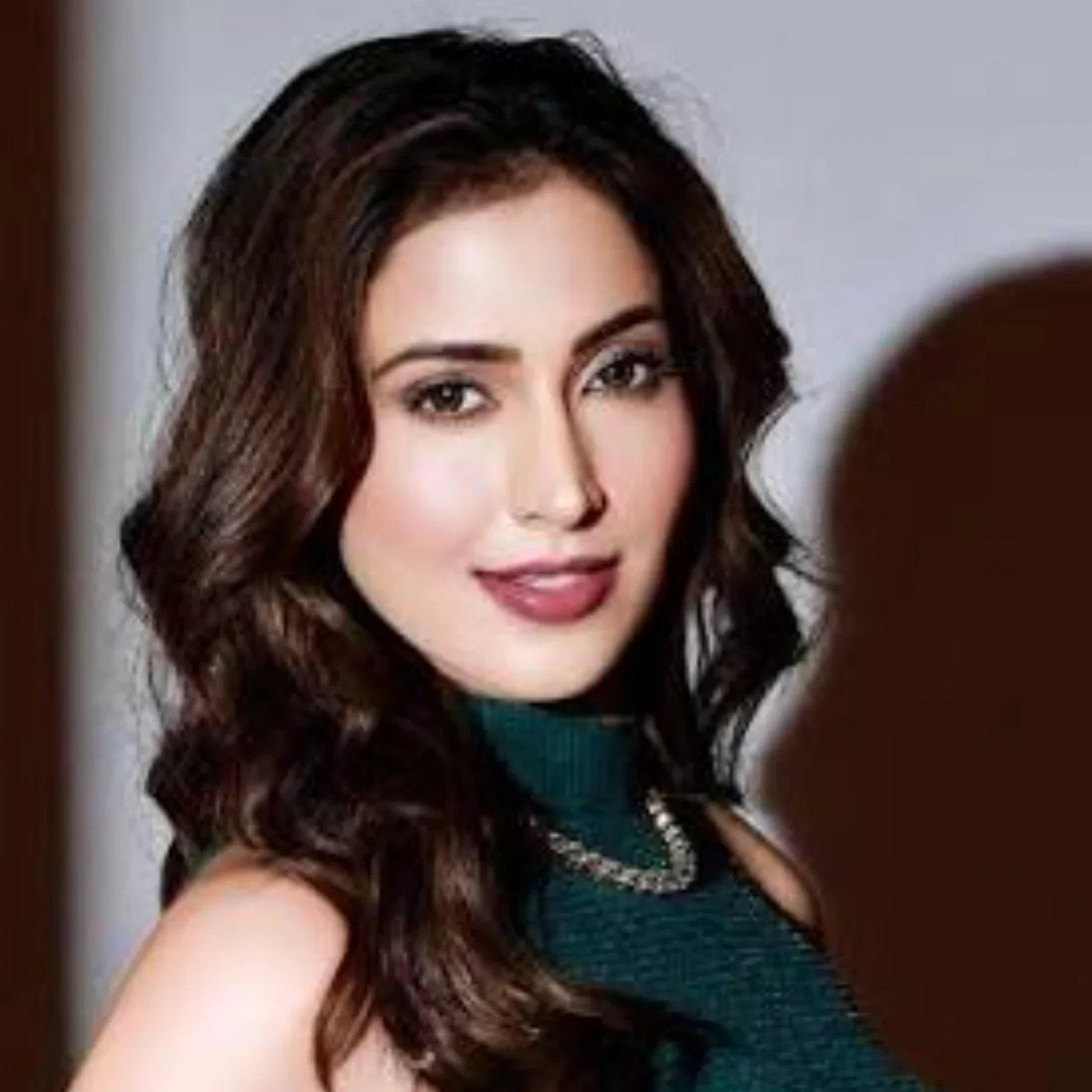 Samaira Sandhu smiling in a stylish green outfit with a chain necklace.