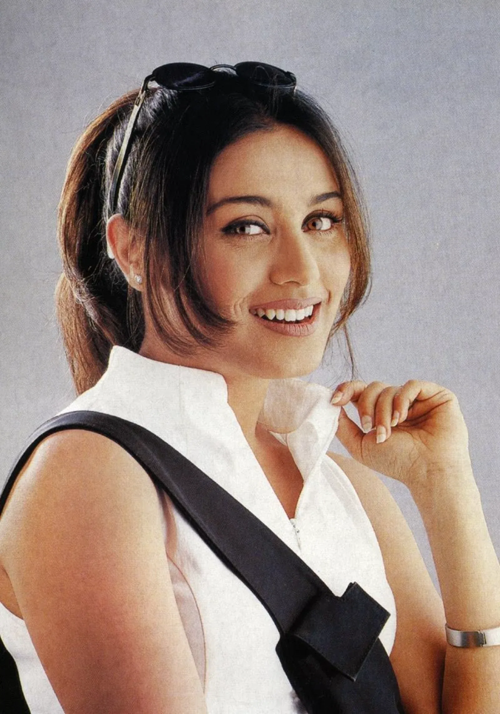 Rani Mukerji smiling in a white outfit with a black strap.