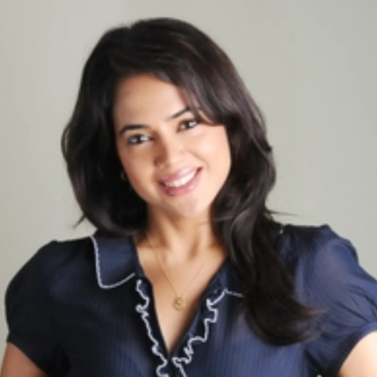 Sameera Reddy smiling in a navy blue top with ruffled collar.
