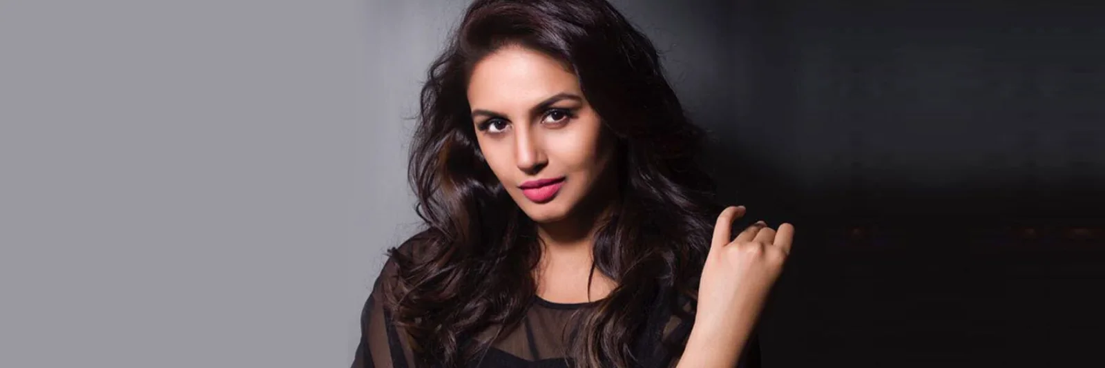 Close-up portrait of Bollywood actress Huma Qureshi with wavy hair posing in a black sheer outfit