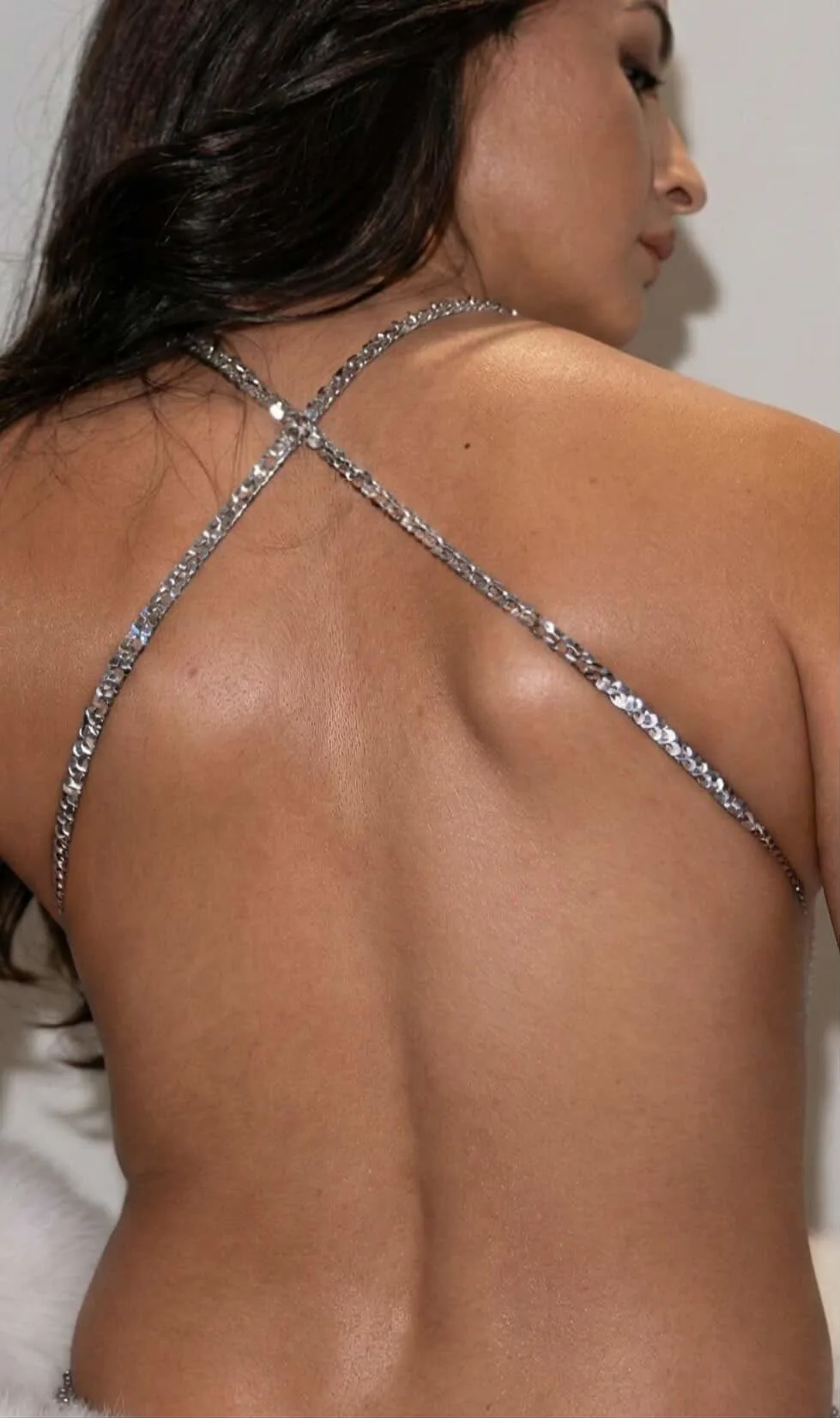 Alia Bhatt posing in a silver sequined backless top showing side profile