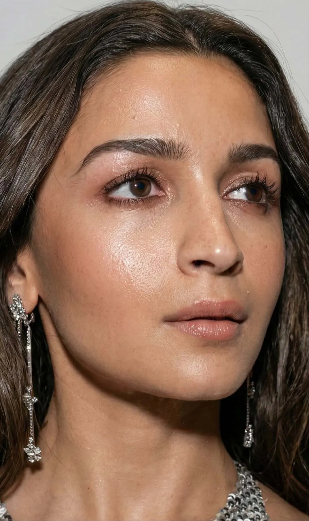 Extreme close-up portrait of Alia Bhatt featuring dewy makeup and silver dangling earrings