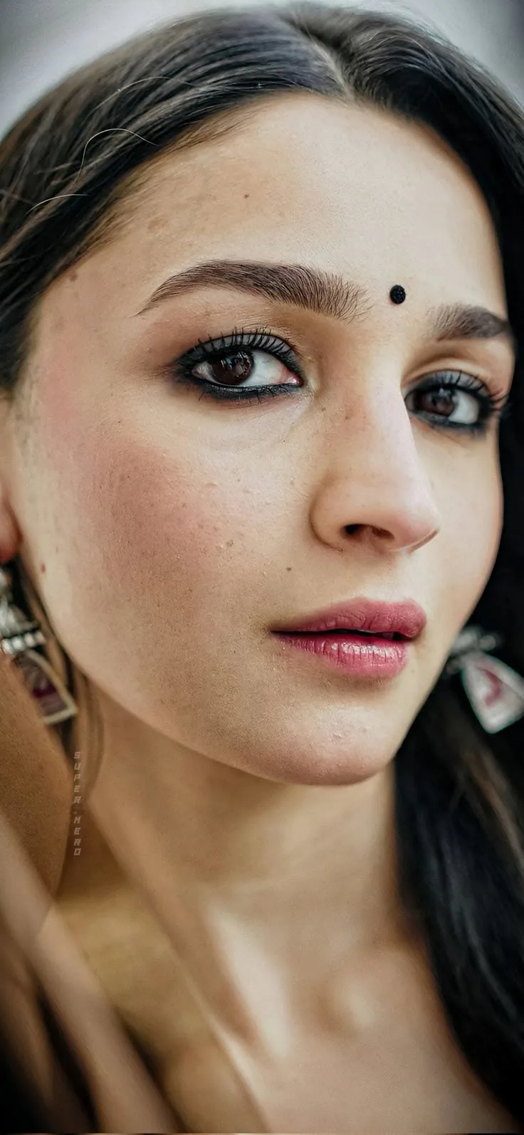 Extreme close-up facial portrait of Alia Bhatt wearing a small black bindi and dark kohl eyeliner.