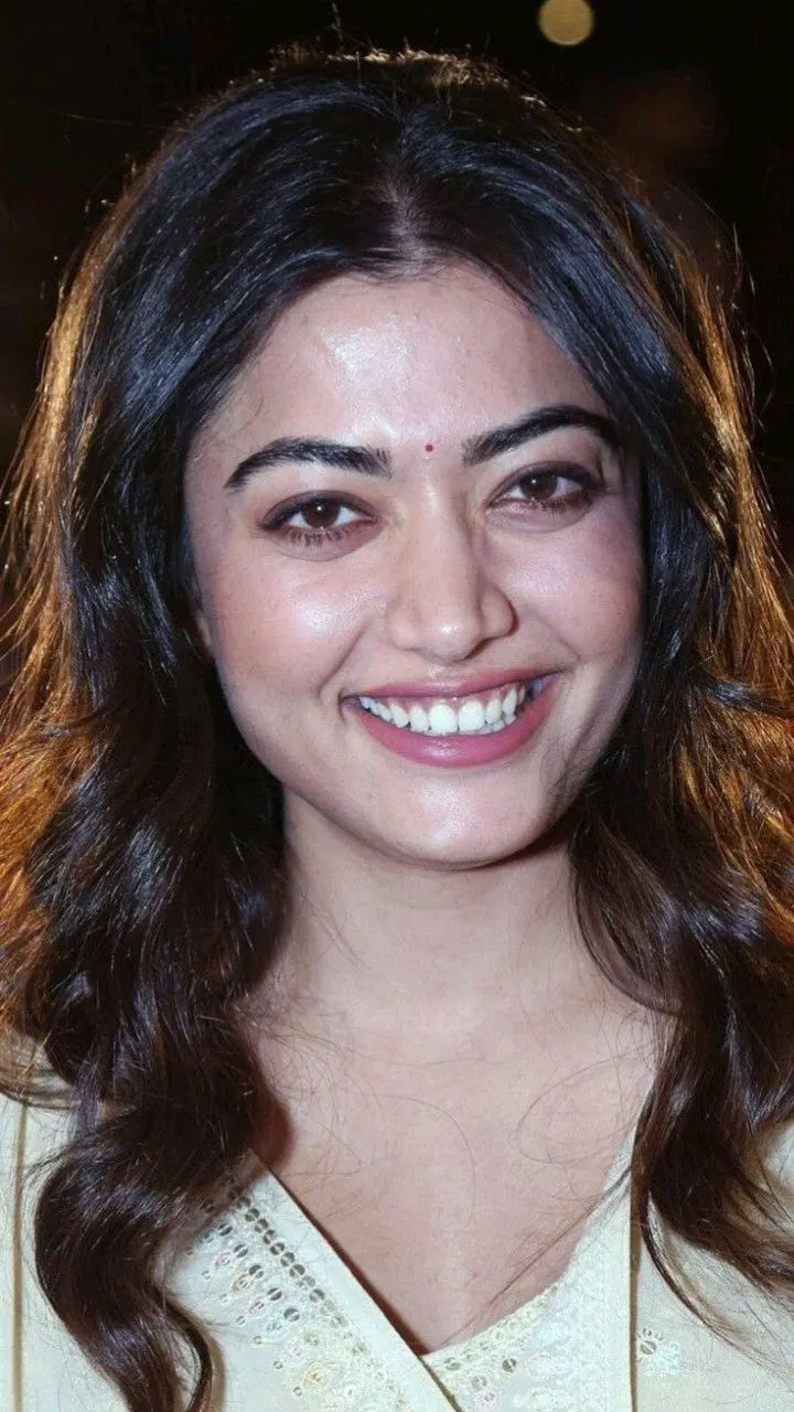 Close-up portrait of Rashmika Mandanna smiling in a cream traditional outfit with a bindi.