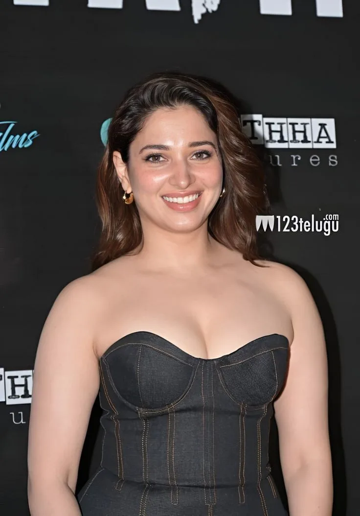 Tamannaah Bhatia smiling in a strapless dark denim corset dress showing cleavage