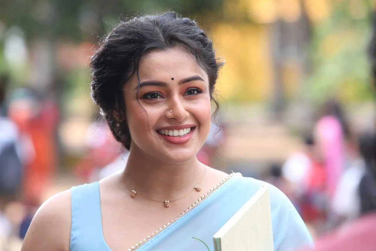 Actress Mokksha smiling in a light blue saree as Meenu Miss in Gatta Kusthi 2