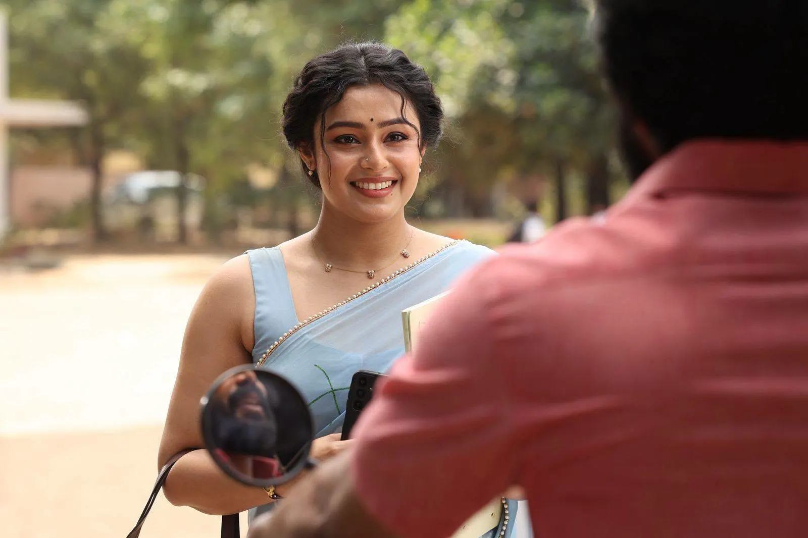 Mokksha smiling in a light blue saree as Meenu Miss in Gatta Kusthi 2