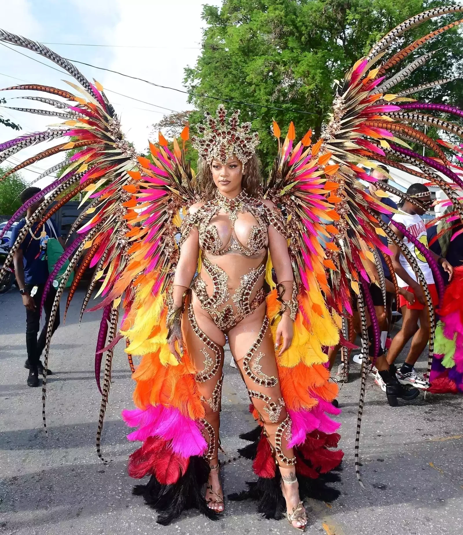 Rihanna wearing a colorful feathered carnival costume with jeweled top and headpiece.